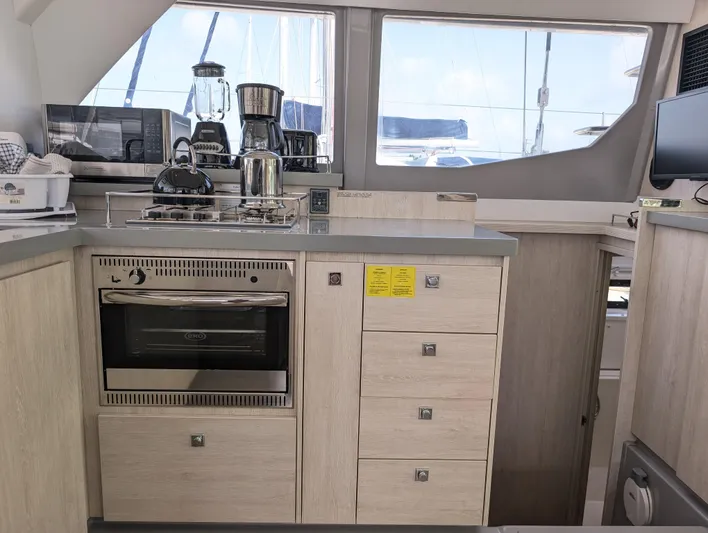 Salty Kiss Yacht Photos Pics Modern kitchen in a 2020 Leopard 45 yacht with appliances and wooden cabinetry.