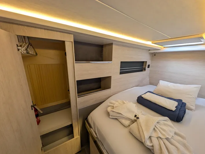 Salty Kiss Yacht Photos Pics Cozy bedroom interior of 2020 Leopard 45 yacht with bed, closet, and ambient lighting.