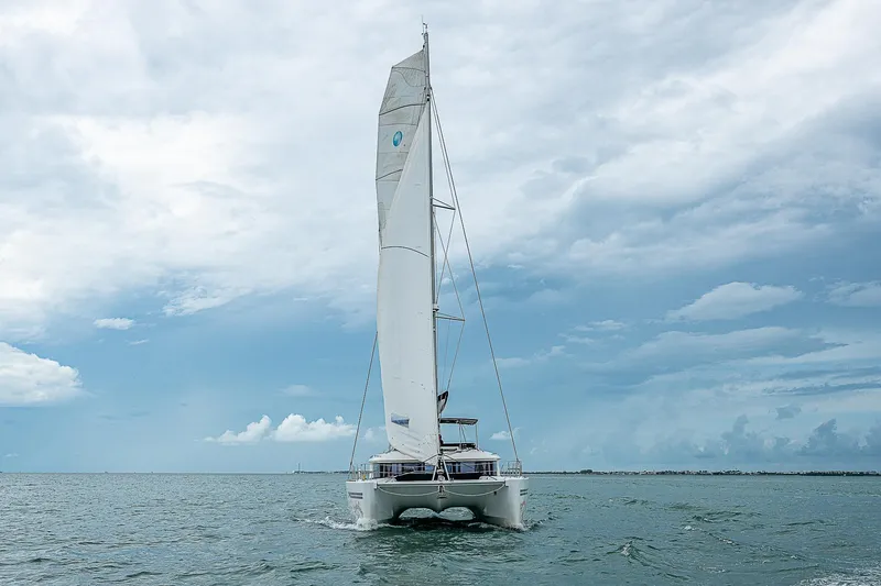 Somewhere Yacht Photos Pics 2018 Lagoon 450 catamaran sailing on open sea under cloudy sky.