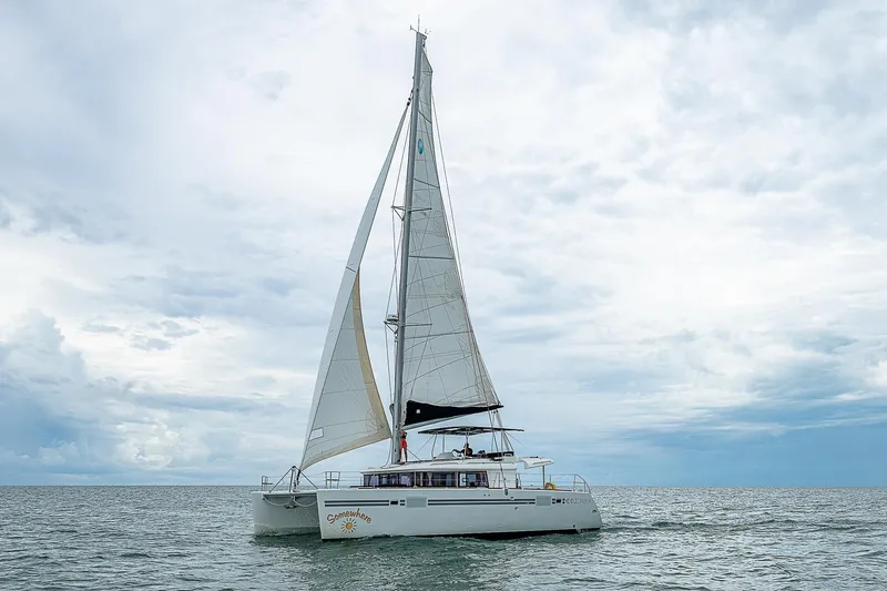 Somewhere Yacht Photos Pics 2018 Lagoon 450 catamaran sailing on open sea under cloudy skies.