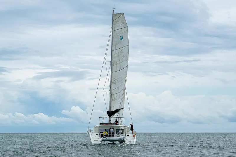 Somewhere Yacht Photos Pics Lagoon 450 catamaran sailing on open sea under cloudy skies, 2018 model.