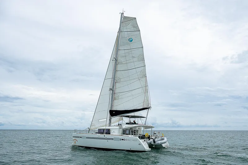 Somewhere Yacht Photos Pics 2018 Lagoon 450 catamaran sailing on open sea under cloudy skies.