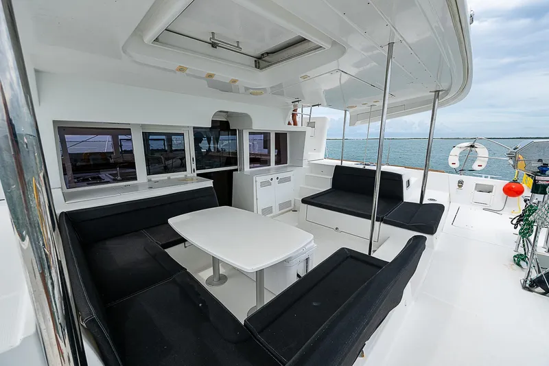 Somewhere Yacht Photos Pics Spacious Lagoon 450 catamaran deck with seating, table, and ocean view, 2018 model.