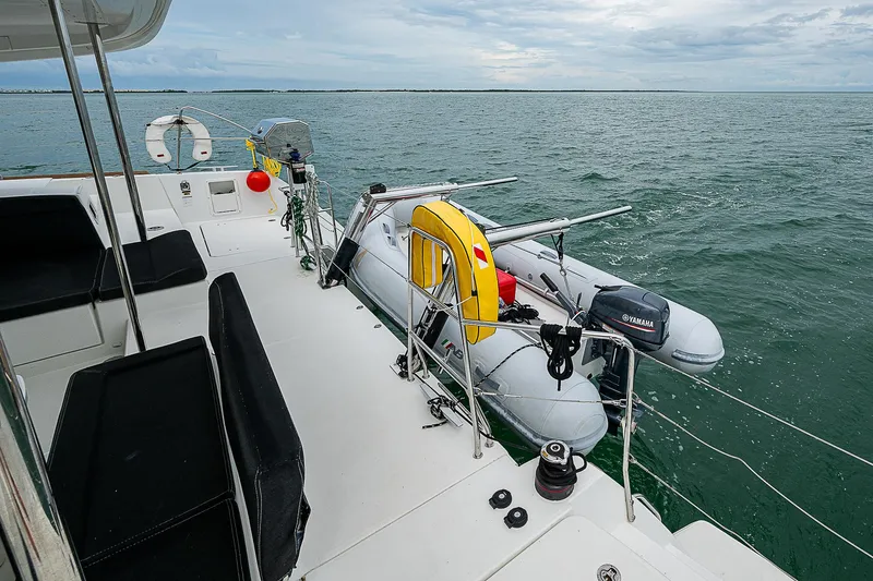 Somewhere Yacht Photos Pics Lagoon 450 catamaran deck with dinghy, 2018 model, on open water.