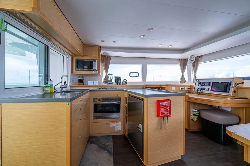 Somewhere Yacht Photos Pics Modern kitchen interior of 2018 Lagoon 450 catamaran with wood cabinetry and ocean views.