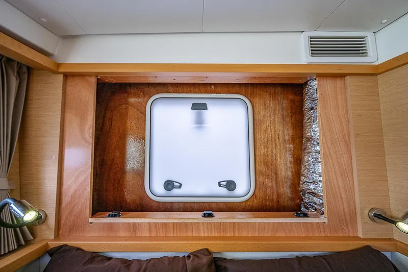 Somewhere Yacht Photos Pics Interior cabin window of 2018 Lagoon 450 catamaran, featuring wood paneling and modern lighting.