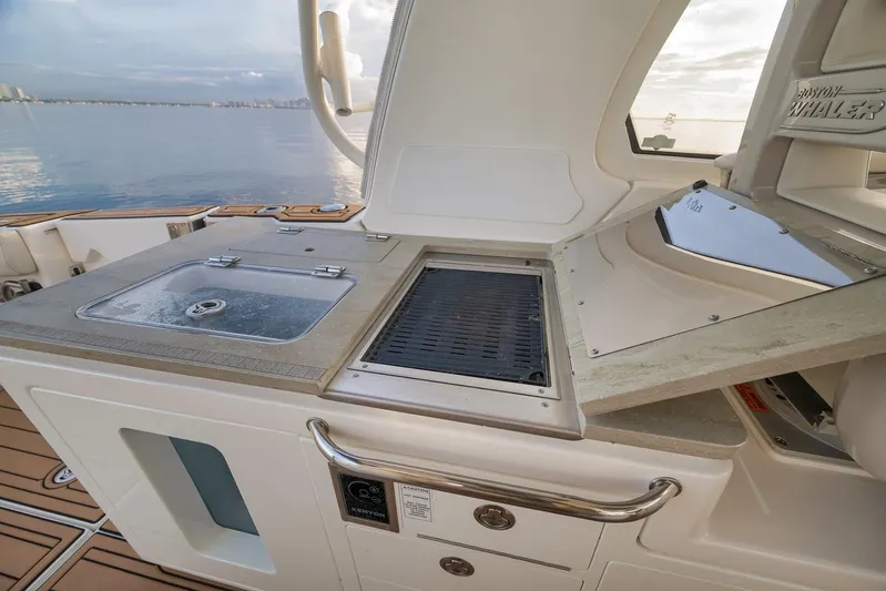  Yacht Photos Pics 2020 Boston Whaler 380 Realm boat kitchen with sink and grill, overlooking serene water.