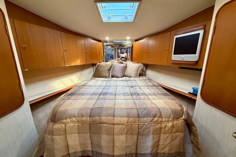  Yacht Photos Pics Luxurious bedroom interior of 2000 Ocean Yachts 48, featuring cozy bedding and wooden cabinetry.