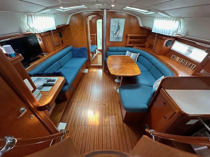 Knot Inspired Yacht Photos Pics Interior of 2002 Beneteau 411 yacht with blue seating and wooden finishes.