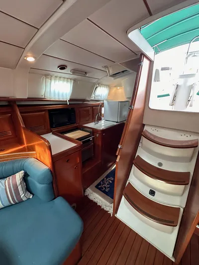 Knot Inspired Yacht Photos Pics Interior of 2002 Beneteau 411 sailboat with cozy seating and compact kitchen area.