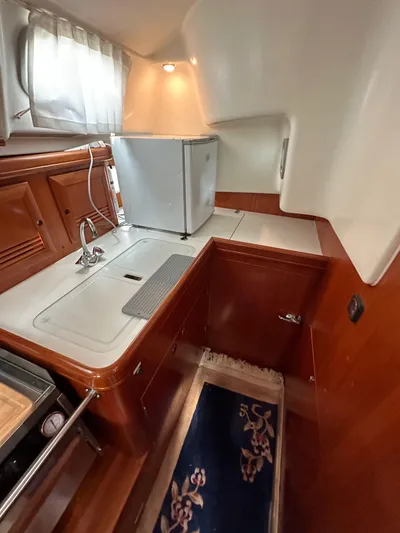 Knot Inspired Yacht Photos Pics 2002 Beneteau 411 yacht kitchen with wood cabinetry, compact fridge, and sink.