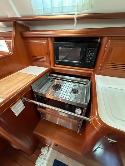 Knot Inspired Yacht Photos Pics 2002 Beneteau 411 yacht kitchen with stove, oven, and microwave in wooden cabinetry.