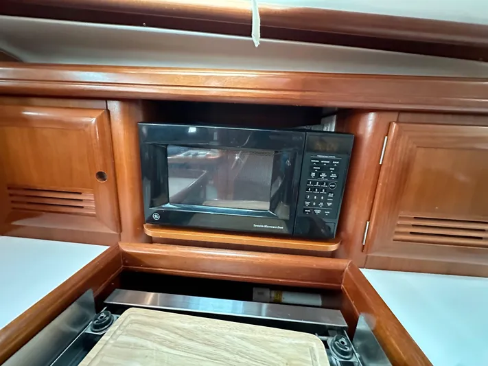 Knot Inspired Yacht Photos Pics Beneteau 411 (2002) yacht kitchen with microwave and wooden cabinetry.