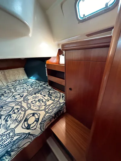 Knot Inspired Yacht Photos Pics Cozy cabin interior of 2002 Beneteau 411 sailboat with wooden furnishings and patterned bedding.
