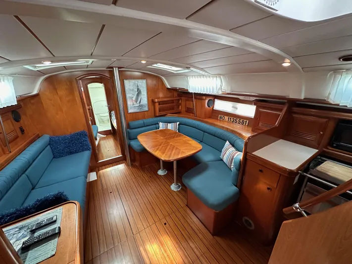 Knot Inspired Yacht Photos Pics Interior of a 2002 Beneteau 411 sailboat with wooden flooring and blue seating.