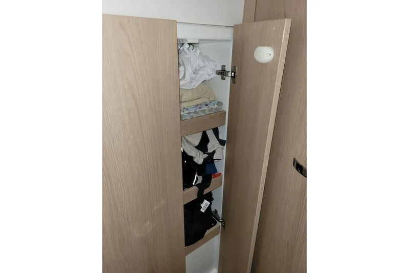  Yacht Photos Pics Wooden cabinet with open doors, revealing neatly stacked clothes on shelves. Bali 4.3, 2019 model.