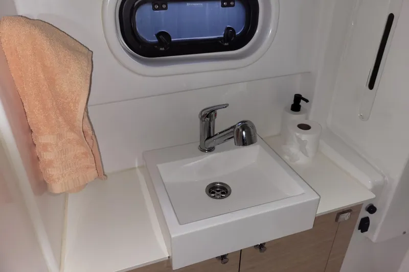  Yacht Photos Pics Compact bathroom sink in a 2019 Bali 4.3 yacht, featuring a towel and toiletries.