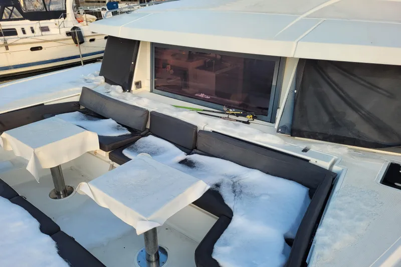  Yacht Photos Pics Snow-covered seating area on a 2019 Bali 4.3 catamaran, docked at a marina.