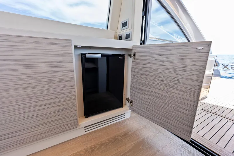  Yacht Photos Pics 2024 Pershing 6X yacht interior with open cabinet and mini fridge, ocean view.