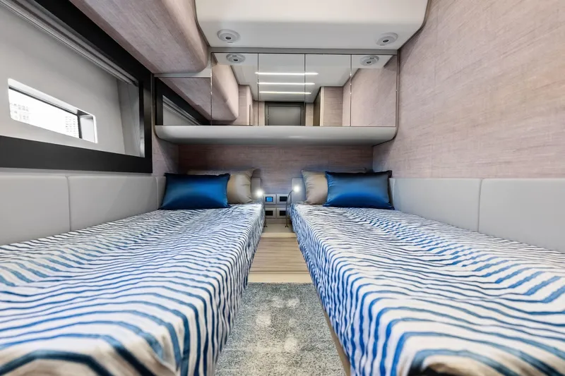  Yacht Photos Pics Luxurious twin cabin interior of 2024 Pershing 6X yacht with striped bedding and modern design.