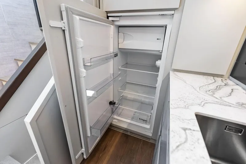  Yacht Photos Pics Open refrigerator in 2024 Pershing 6X yacht kitchen, featuring modern design and marble countertop.
