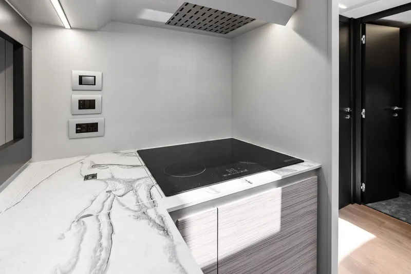  Yacht Photos Pics Modern kitchen interior of 2024 Pershing 6X yacht with sleek cooktop and marble countertop.