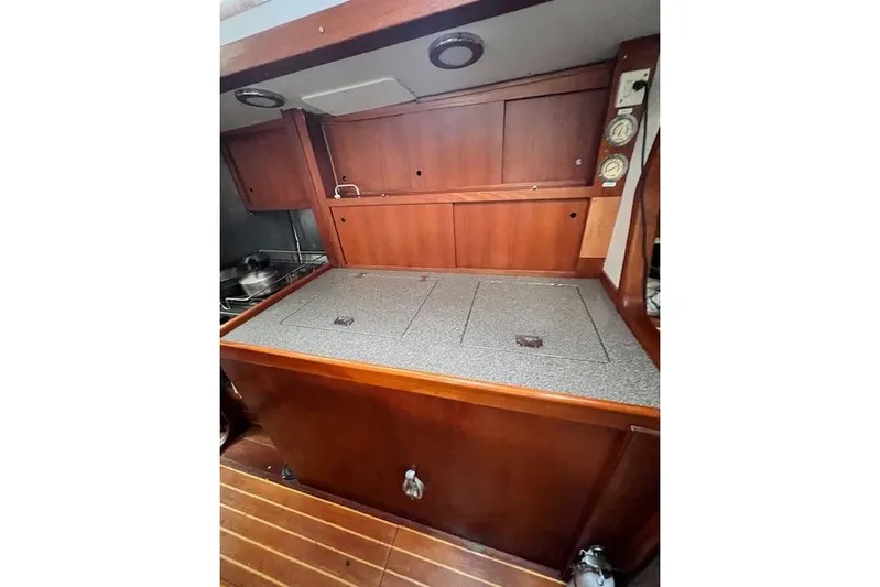 Yacht Photos Pics Wooden interior of 1985 Robert Clark Ketch, featuring a compact galley with storage.