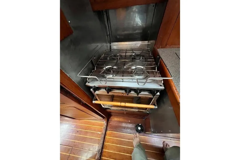  Yacht Photos Pics Galley stove in 1985 Robert Clark Ketch, featuring wooden flooring and compact design.