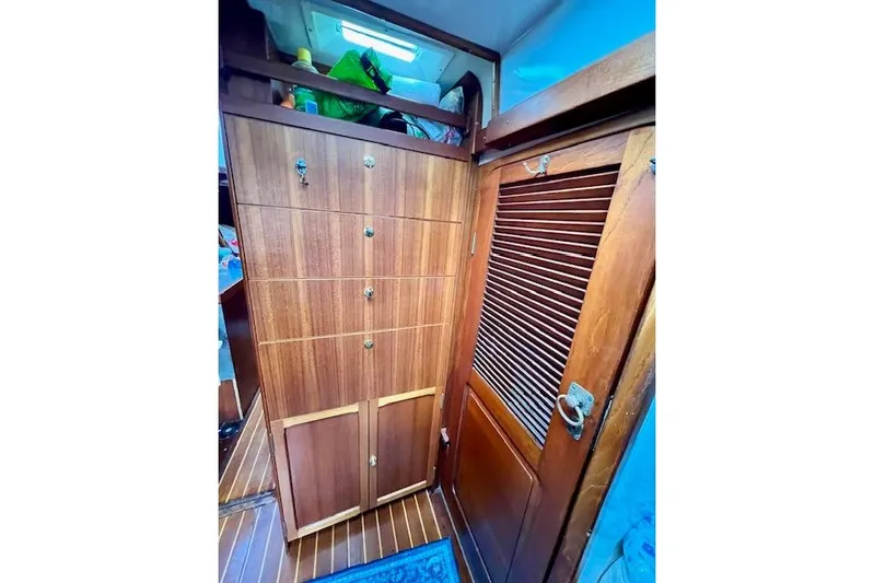  Yacht Photos Pics Wooden interior of 1985 Robert Clark Ketch, featuring cabinets and a louvered door.