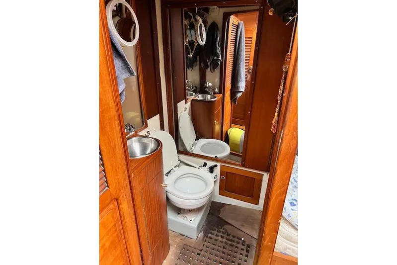  Yacht Photos Pics 1985 Robert Clark Ketch yacht bathroom with wooden cabinetry and compact fixtures.