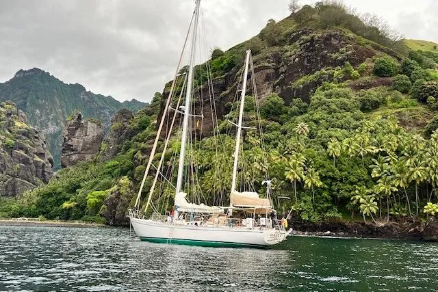  Yacht Photos Pics Sailboat "Robert Clark Ketch 1985" anchored near lush, rocky island coastline.