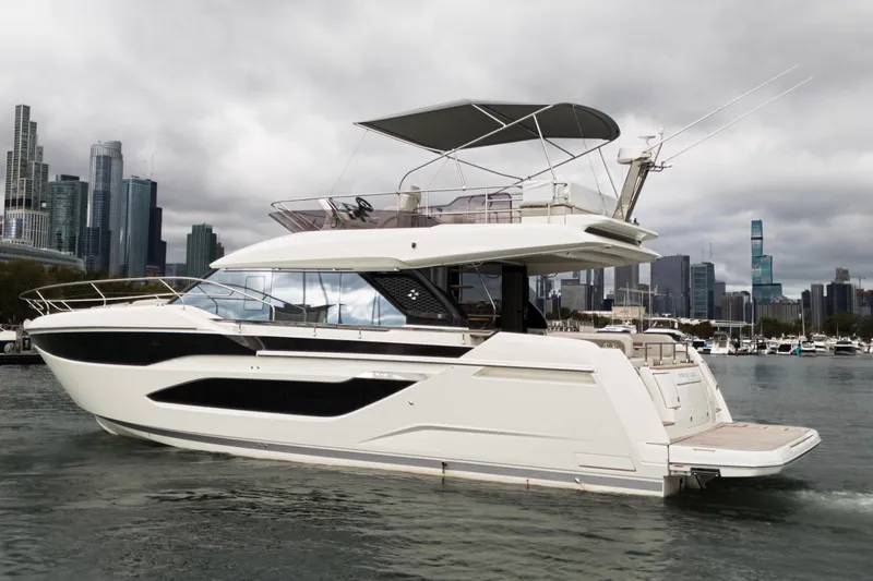  Yacht Photos Pics Luxury 2026 Prestige F4.9 yacht cruising near city skyline under cloudy skies.
