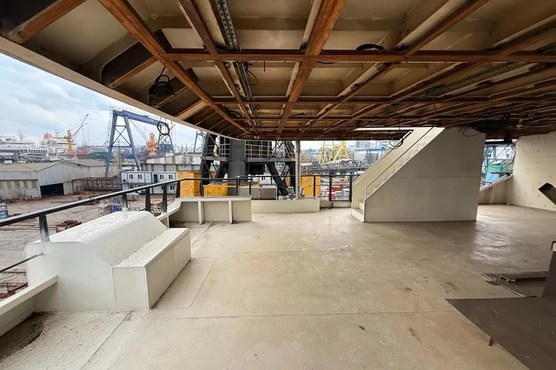 Nirvana Yacht Photos Pics Open deck area on a 2027 Soyaslan Custom ship, overlooking a busy shipyard.