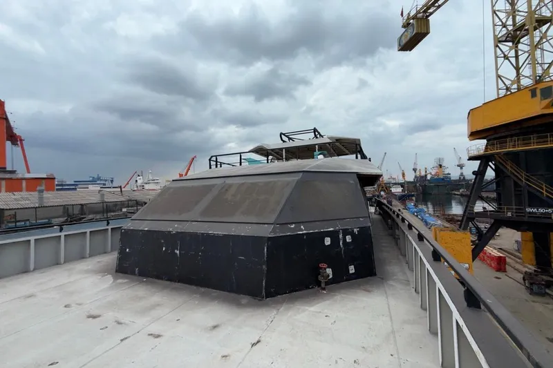 Nirvana Yacht Photos Pics Industrial shipyard with Soyaslan Custom 2027 vessel under cloudy sky.