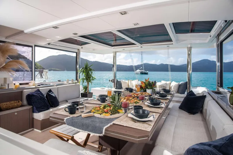 Ad Astra Yacht Photos Pics Luxurious Bali 5.4 yacht interior with dining setup, ocean view, and mountains in the background.