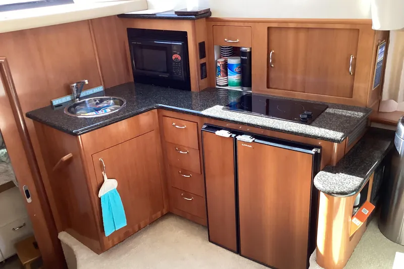 Fun Coupons Yacht Photos Pics 2005 Carver 41 Cockpit Motor Yacht kitchen with wood cabinetry, microwave, and compact fridge.