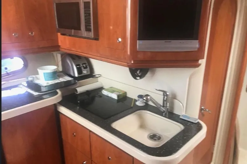  Yacht Photos Pics 2007 Four Winns 278 Vista boat kitchen with sink, microwave, and wooden cabinets.