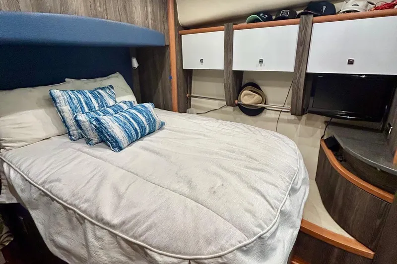 Redeye Yacht Photos Pics Cozy bedroom in 2012 Tiara Yachts 48 CNV with blue pillows and wooden cabinetry.