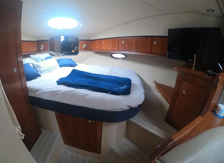 Grand Cru Yacht Photos Pics 2005 Cruisers Yachts 340 Express cabin with bed, TV, and wooden cabinetry.