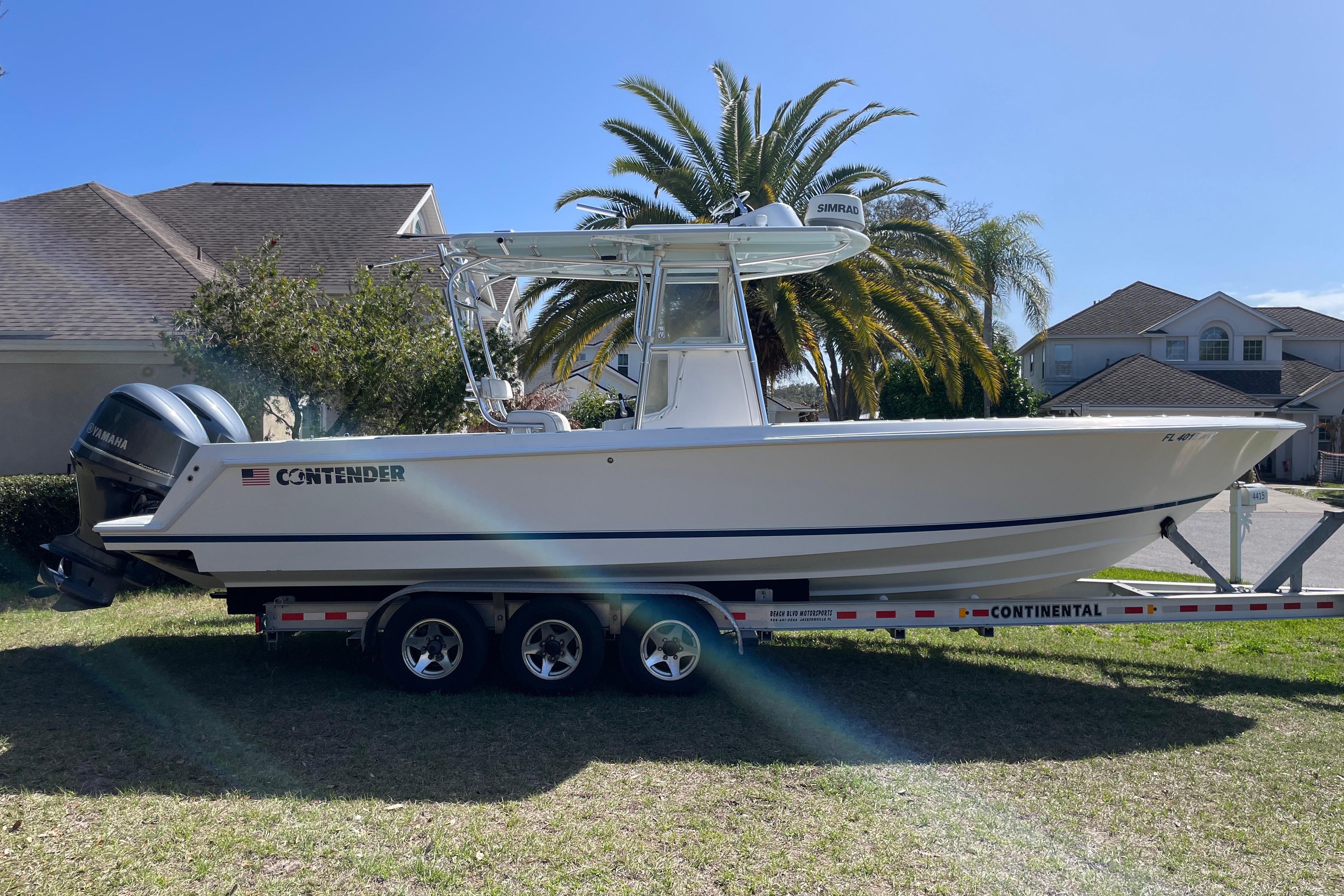 2008 Contender 27 Tournament boat on trailer, parked in residential area with palm trees.
