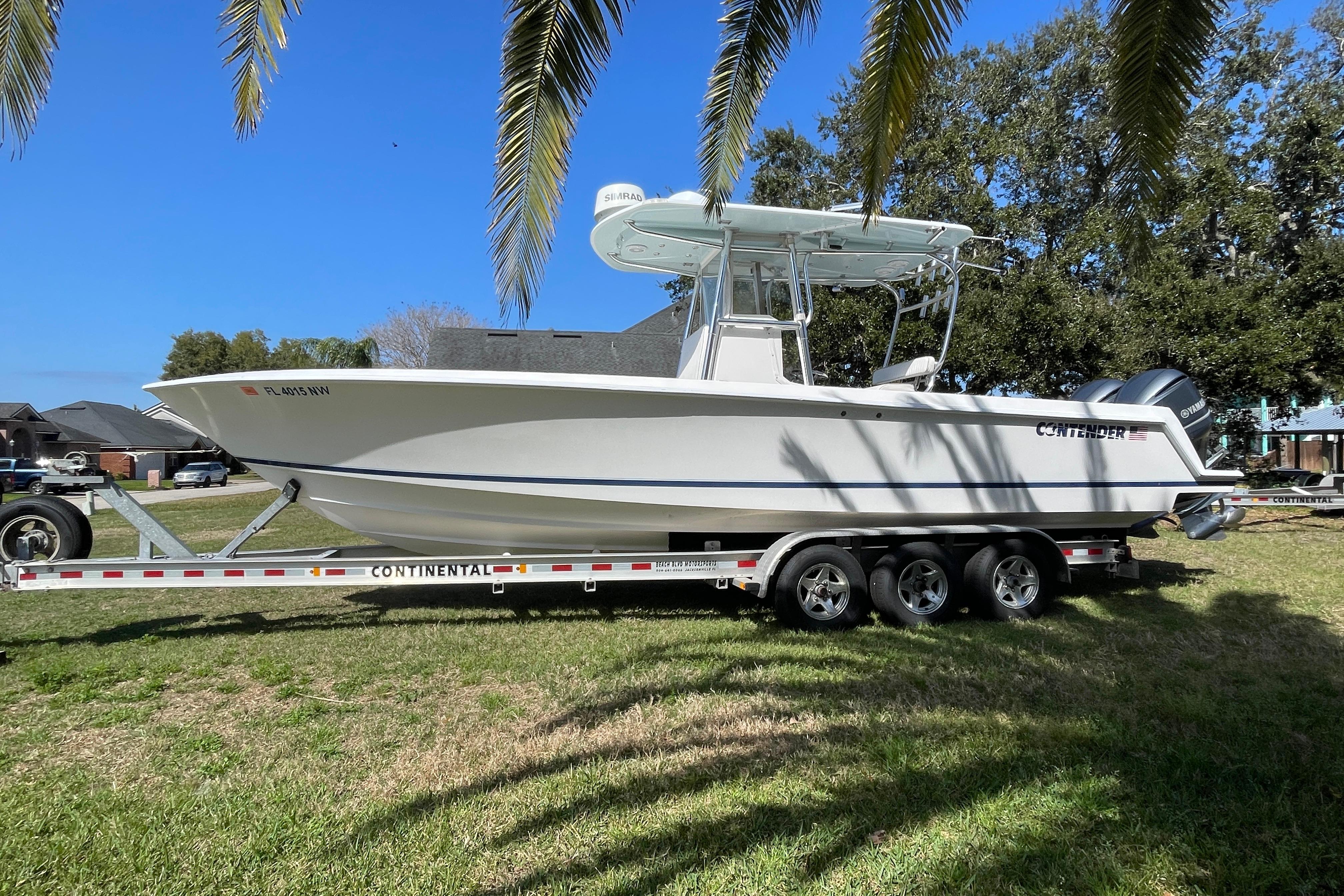 2008 Contender 27 Tournament boat on trailer, parked on grass under palm trees.