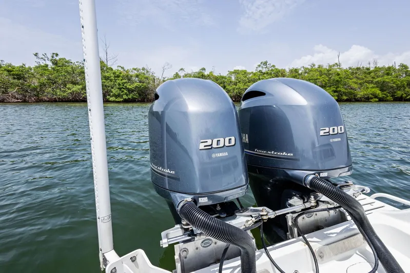  Yacht Photos Pics Twin Yamaha 200 outboard motors on a 2016 Yellowfin 26 Hybrid boat, near lush shoreline.