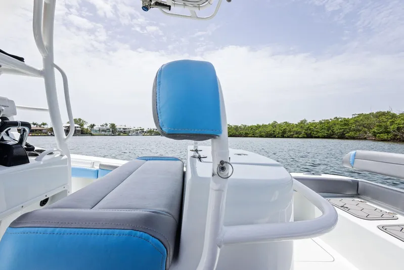  Yacht Photos Pics 2016 Yellowfin 26 Hybrid boat interior with blue and gray seating, overlooking calm water and greenery.