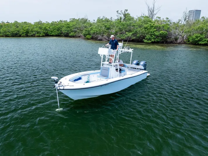  Yacht Photos Pics 2016 Yellowfin 26 Hybrid boat on calm water near lush shoreline.