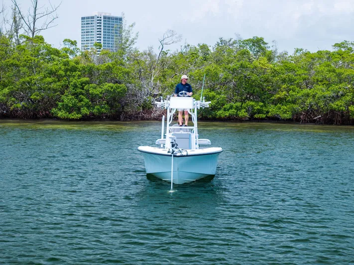  Yacht Photos Pics 2016 Yellowfin 26 Hybrid boat on calm water near lush greenery.