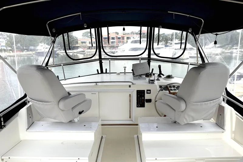 Summer Wind Yacht Photos Pics Interior view of 1989 Grand Banks 46 Classic yacht helm with two seats and marina backdrop.