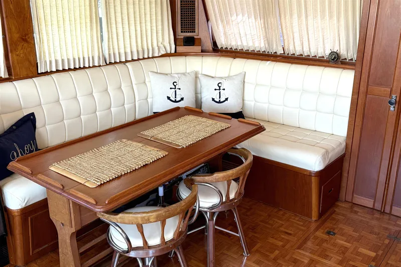 Summer Wind Yacht Photos Pics 1989 Grand Banks 46 Classic yacht interior with wooden table, cushioned seating, and nautical decor.