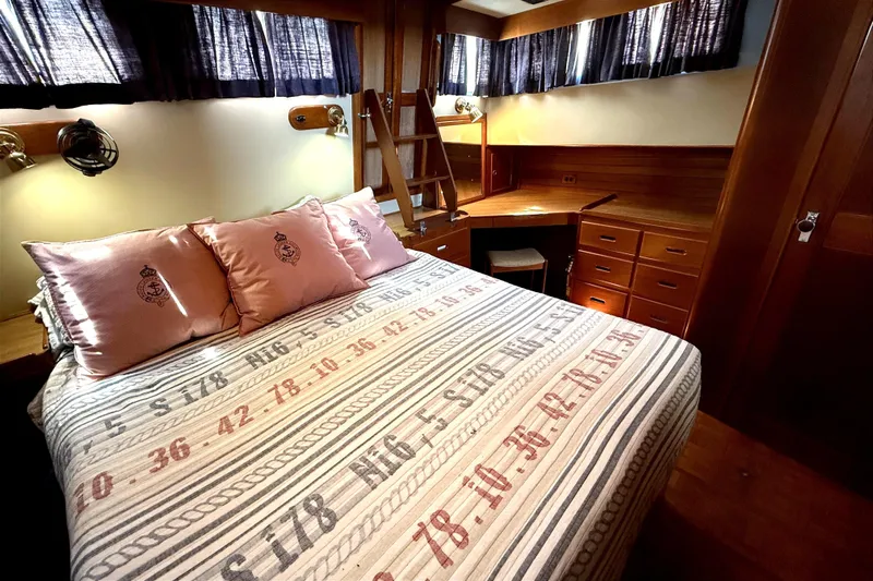 Summer Wind Yacht Photos Pics Cozy bedroom in 1989 Grand Banks 46 Classic yacht with nautical-themed bedding and wooden furnishings.