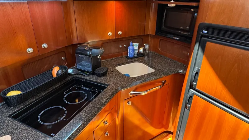  Yacht Photos Pics 2005 Sea Ray 390 Motor Yacht kitchen with stove, sink, and wooden cabinetry.