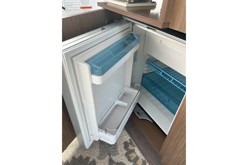  Yacht Photos Pics Open refrigerator inside 2024 Beneteau Antares 9 boat, showcasing interior shelves and compartments.
